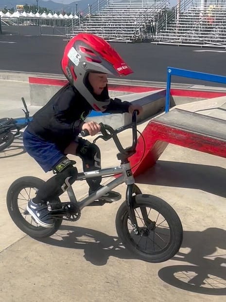 Child on a bike doing a small jump at a skatepark